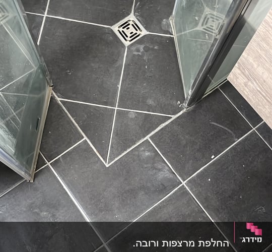 רצפת מקלחת עם אריחים שחורים וניקוז